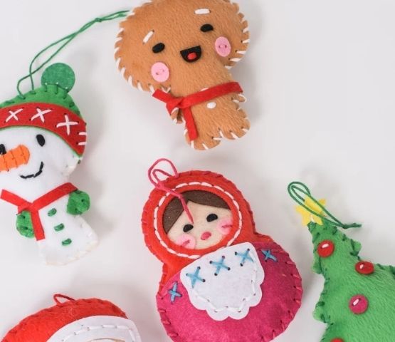 Felt Christmas decorations, including a gingerbread man, a Christmas tree, a Russian doll, a snowman and colourful decorations.