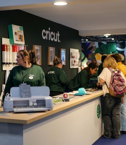 Cricut stand with cutting machine demonstrations and visitor queues.