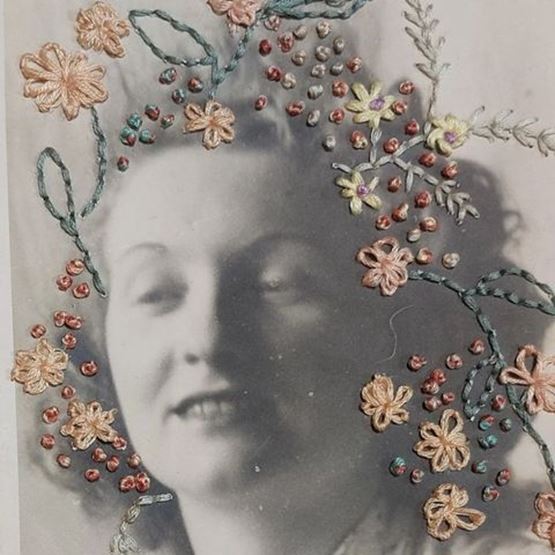 Photographie ancienne décorée de broderies florales colorées.
