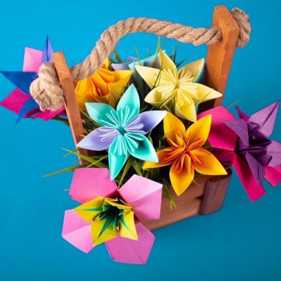 Bouquet de fleurs colorées en origami dans un panier en bois.