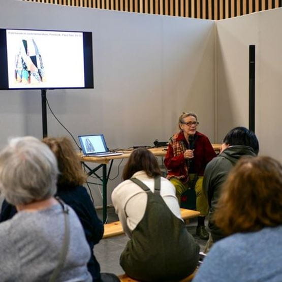 Conférencière animant un atelier créatif devant un petit public.