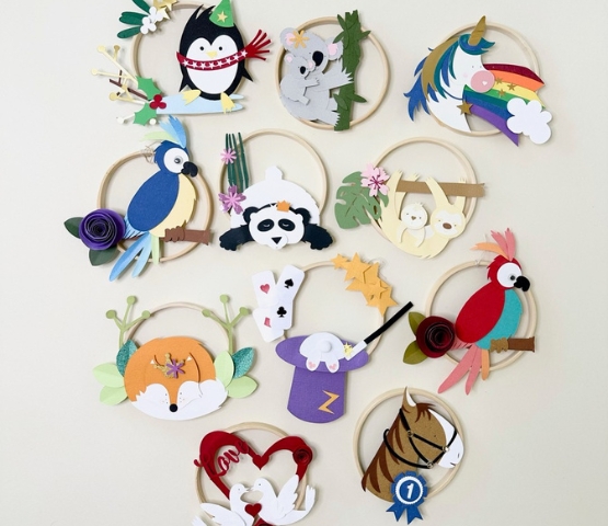 A series of handmade creations in coloured paper featuring animals, rainbows and playful motifs for children