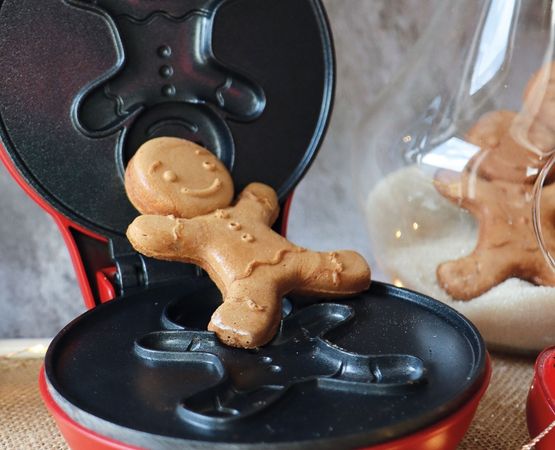 Biscuit en forme de bonhomme en pain d’épices dans un appareil de cuisson à empreintes festives.