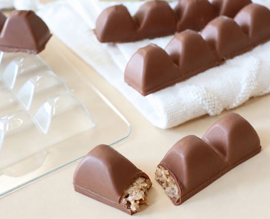 Barres de chocolat au lait moulées, dont une coupée pour révéler sa garniture intérieure aux éclats croquants.