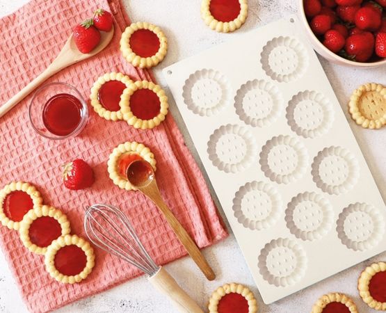 Golden tartlet bases displayed next to a silicone mould with round indentations.