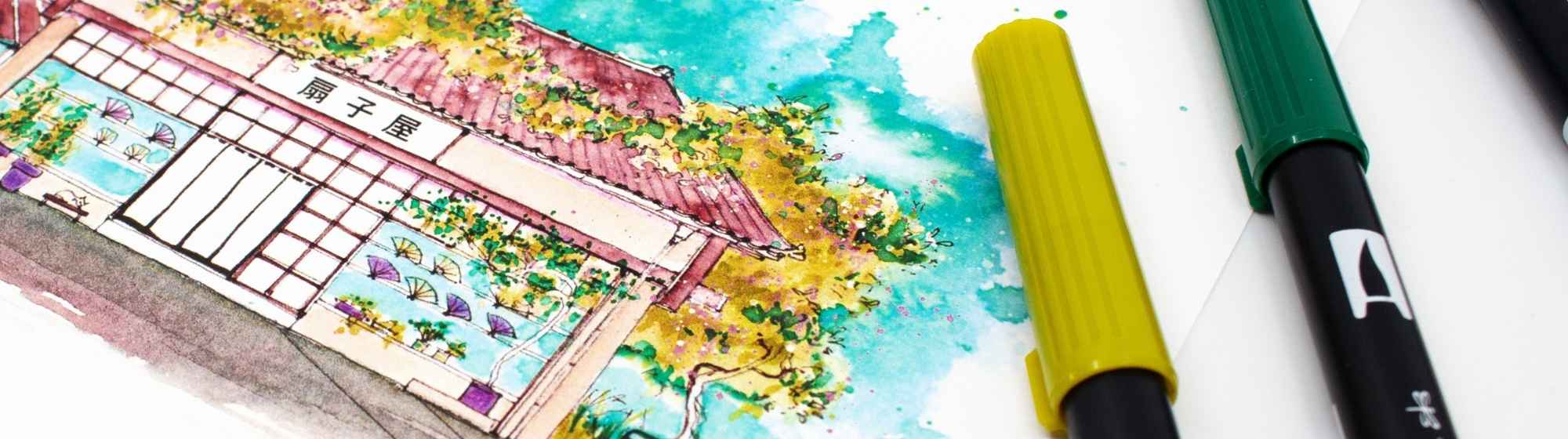 Close-up of a colourful Japanese watercolour depicting a traditional house, surrounded by coloured markers.