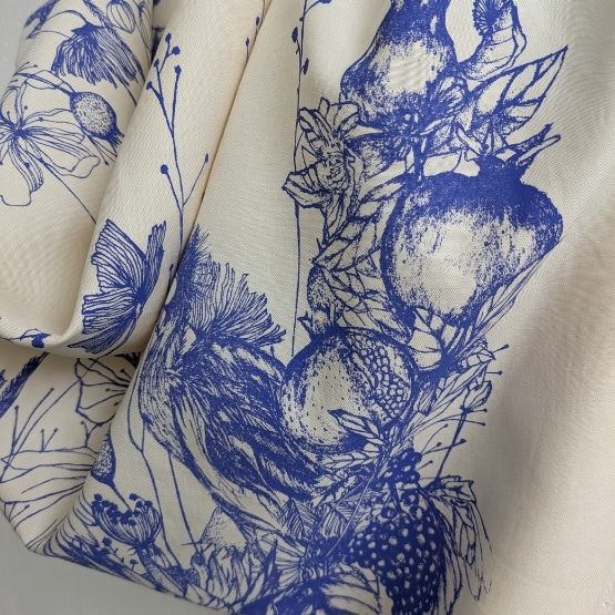 White fabric printed with floral and fruity motifs in blue ink.