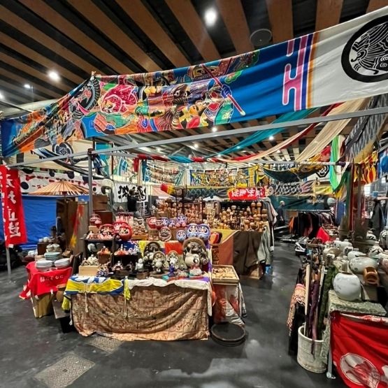 Stand decorated with colourful Japanese banners, with handicrafts and figurines on display.