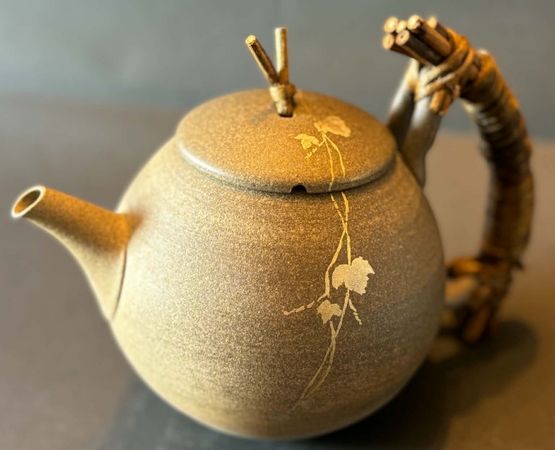 Petites sculptures en bois représentant des chats japonaises, avec des sourires et des colliers, exposées sur un comptoir en bois.
