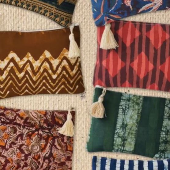 Collection of cushions in tribal and indigo motifs, with white fringes, arranged in an orderly fashion on a beige background.