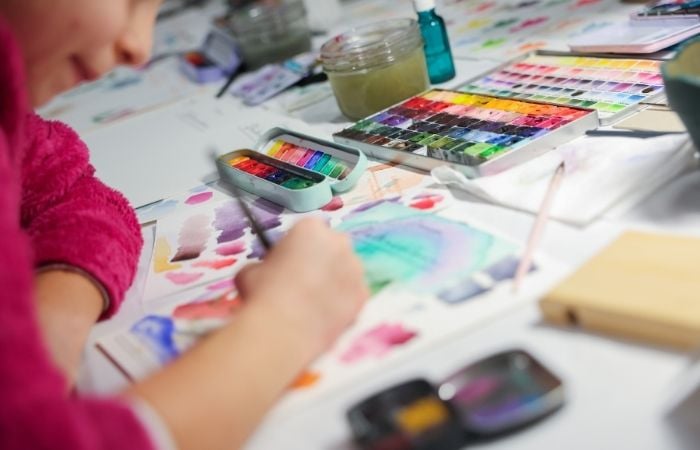 Enfant présentant une création en laine en forme d’arc-en-ciel lors d’un atelier créatif