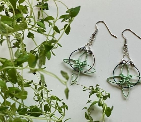 Création artisanale de bijoux en fil métallique et plantes, capturant une esthétique minimaliste.