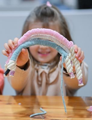 Enfant présentant une création textile colorée réalisée à la main lors d’un atelier créatif.