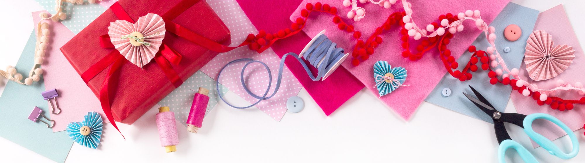 Loisirs créatifs rose et rouge pour la Saint Valentin : papier, ciseaux, rubans, fils de couture,...