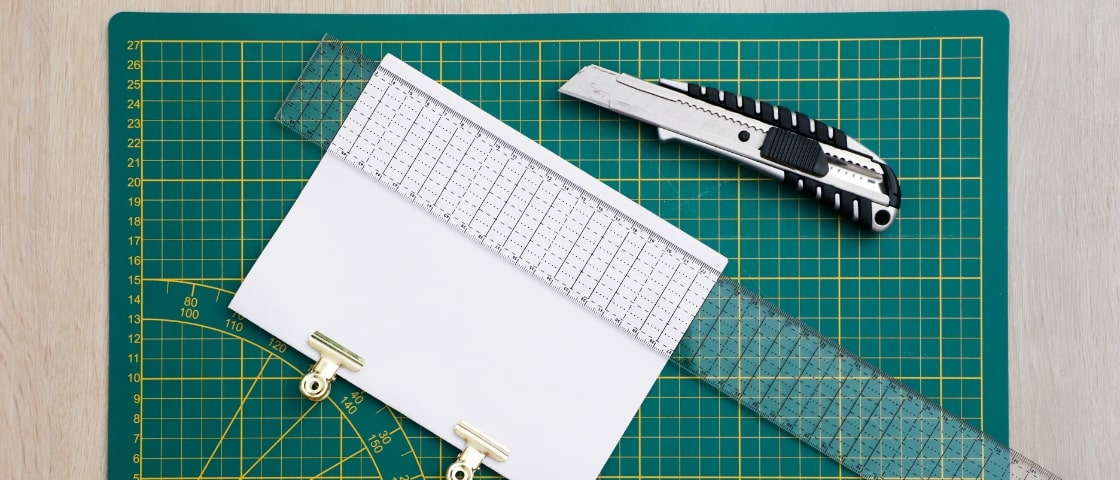 Handmade DIY travel journal materials: cutter, sheet of paper and ruler