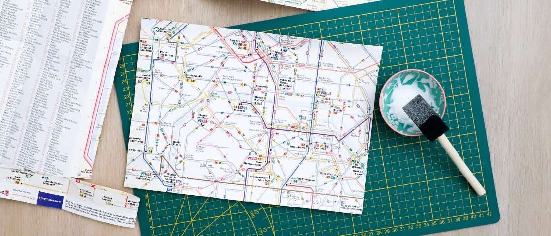 Handmade DIY travel journal materials: Paris metro map, pot of glue and paintbrush
