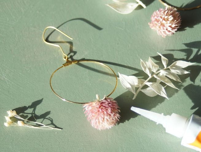 Boucles dorées décorées de fleurs séchées blanches et roses.