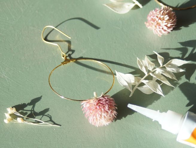 Boucles dorées décorées de fleurs séchées blanches et roses.