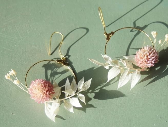 Une boucle en cours de création avec fleur rose séchée collée sur le support doré.