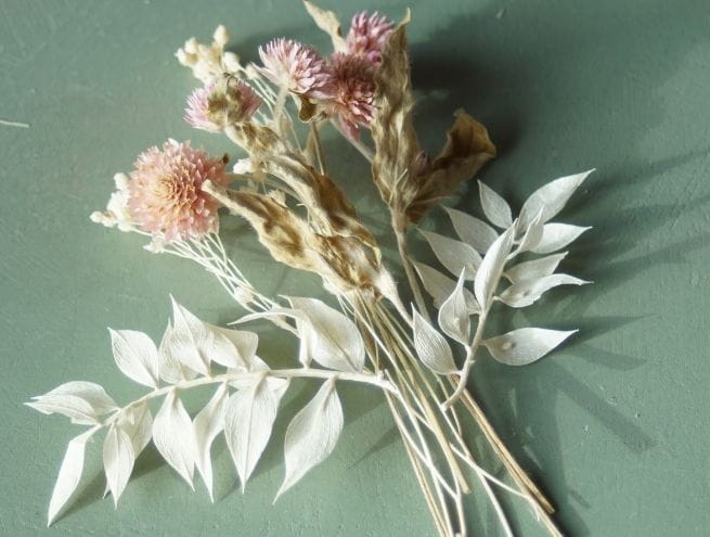 Composition de fleurs séchées roses et blanches prêtes à être fixées pour une boutonnière.