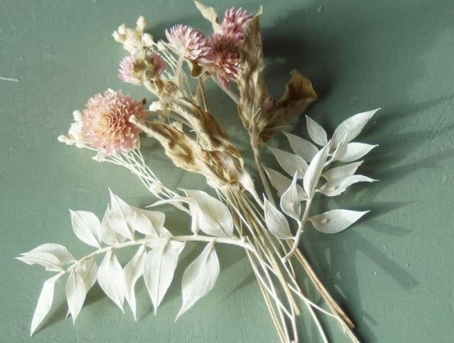 Composition de fleurs séchées roses et blanches prêtes à être fixées pour une boutonnière.