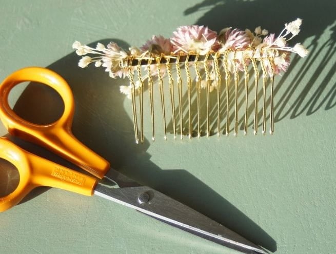 Peigne entièrement décoré de fleurs séchées pastel en gros plan.