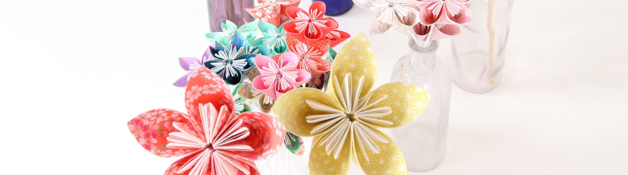 Several bouquets of colourful origami flowers in vases