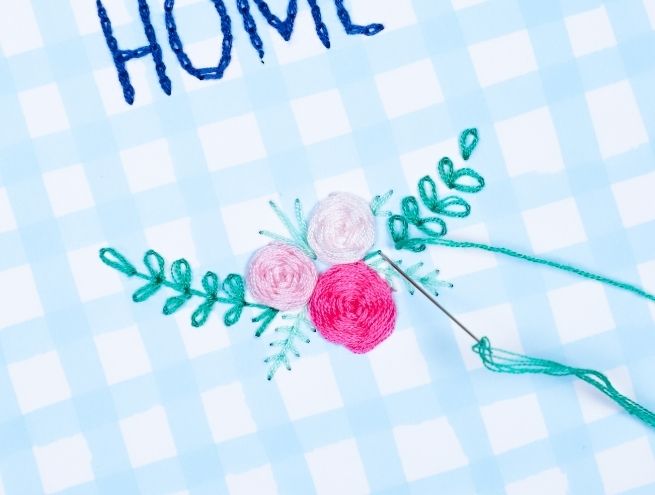 Floral design embroidered on paper with pink flowers and green leaves under the word HOME.