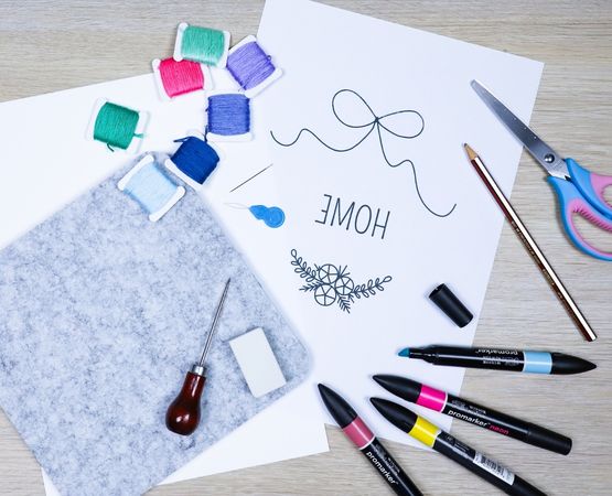 Materials for embroidery on paper, including thread, needles, scissors and felt pens.