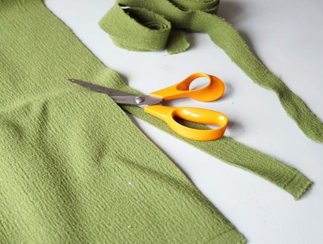 Étape 1 de la fabrication d'une couronne de Noël avec un cercle en bois et du tissu vert.