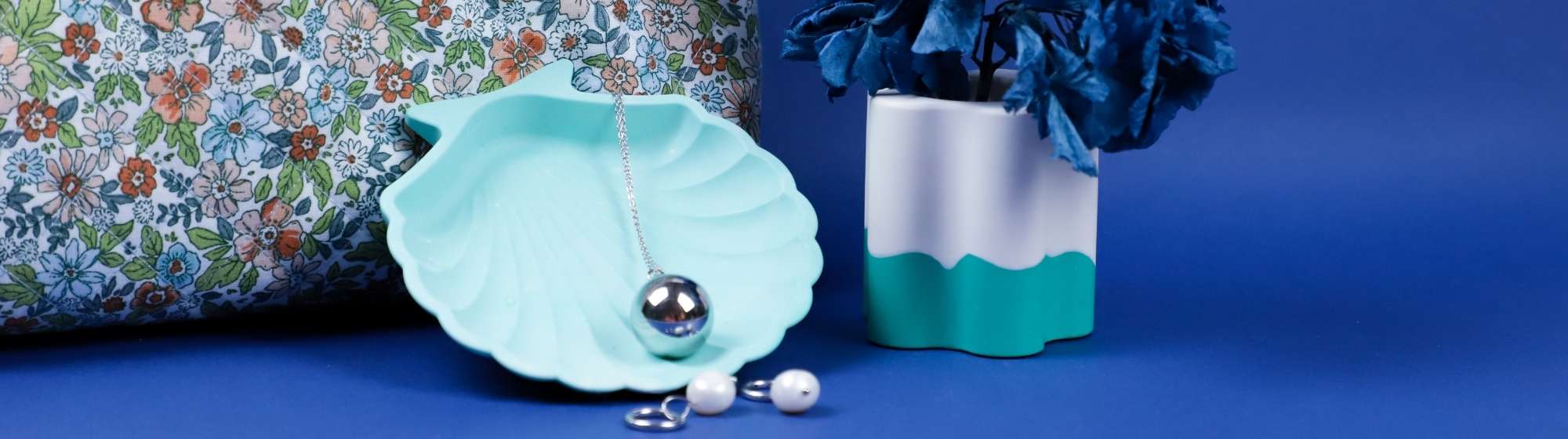 Set the scene with a Jesmonite pot, a blue shell tray, jewellery and a floral bag.