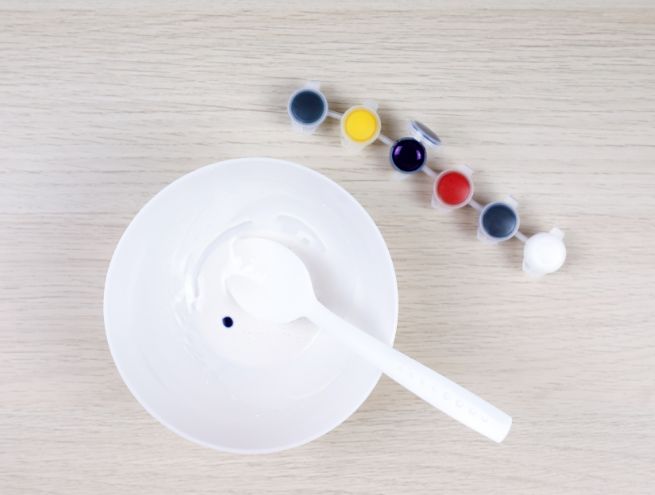 Drop of blue pigment added to a bowl of white Jesmonite using a spoon.