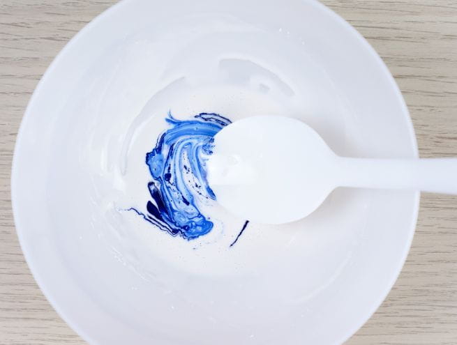 Pigment bleu en train d’être mélangé à la Jesmonite blanche dans un bol.