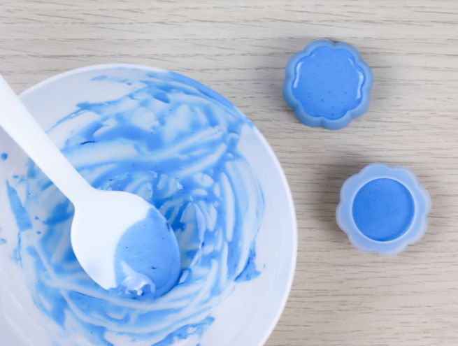 Jesmonite blue paste mixed in a bowl and poured into flower-shaped moulds.