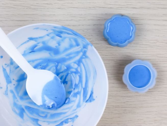 Pâte bleue Jesmonite mélangée dans un bol et coulée dans des moules en forme de fleurs.