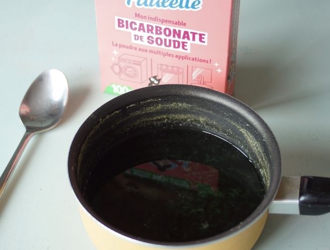 Dark liquid extracted from cabbage with a box of bicarbonate of soda at the back.