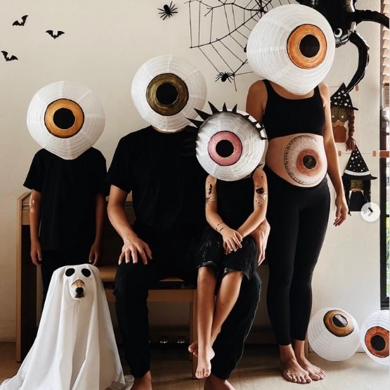 Family dressed up with lanterns in the shape of giant eyes for Halloween.