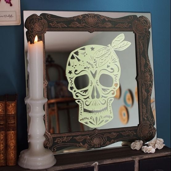 Miroir orné d’une tête de mort décorative style calavera et d’une bougie allumée.