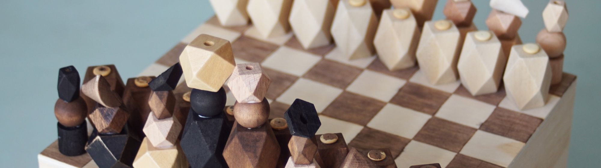 Zoom sur les pièces géométriques en bois placées sur le plateau de l’échiquier