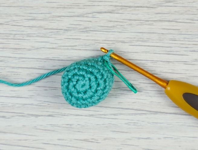 Début du jouet pour bébé au crochet avec un cercle de mailles serrées réalisé en fil vert et bleu clair.