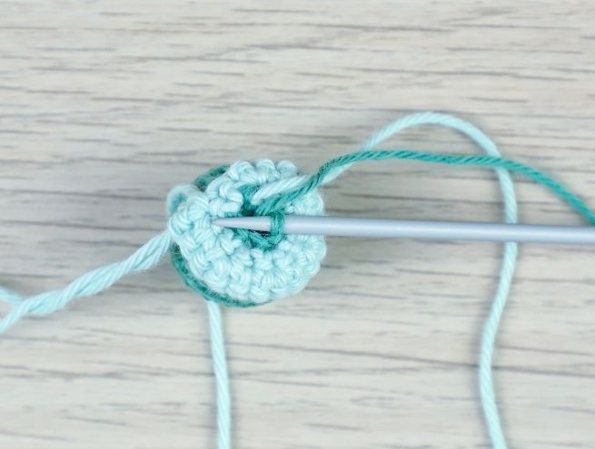 Étape de crochet du jouet pour bébé montrant un cercle de mailles serrées avec un crochet et un marqueur de maille.