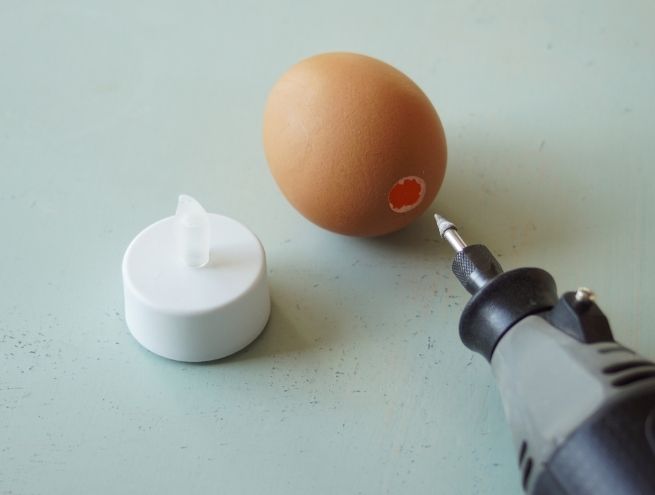 Perçage d’un œuf avec une mini perceuse pour vider l’intérieur avant décoration.