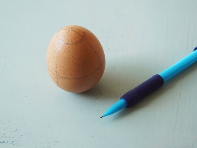 Œuf cru sur lequel un motif est dessiné au crayon avant la gravure.