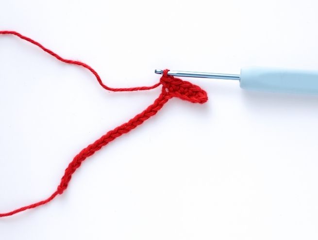 Réalisation d’une pochette de téléphone au crochet avec un fil rouge en cours de création