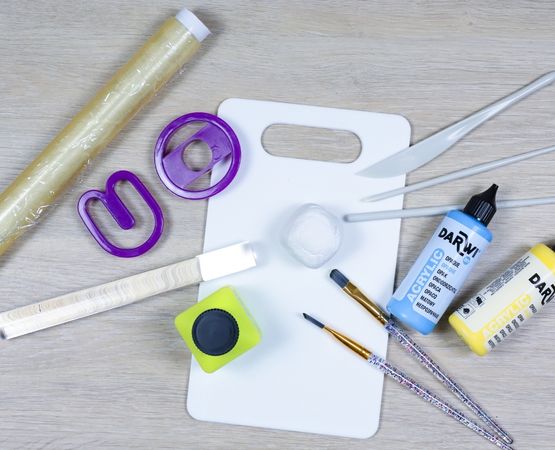 Materiel necessaire pour creer un prenom en pate autodurcissante avec peinture, pinceaux, rouleau et emporte-pieces lettres.