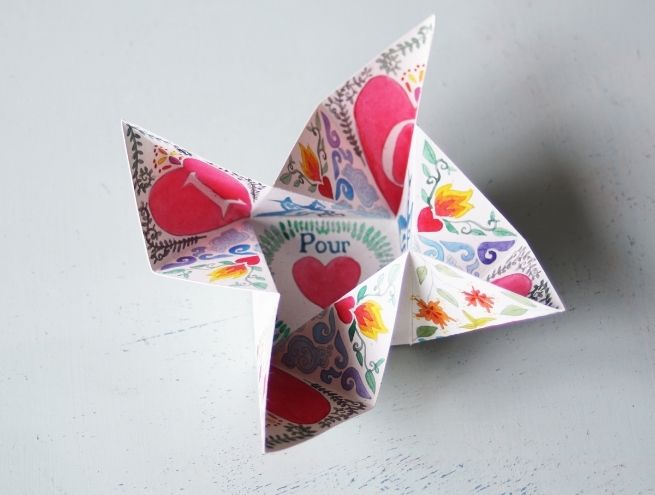 Puzzle en papier coloré en forme de fleurs, avec des cœurs et des oiseaux, déplié.