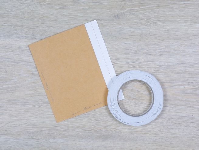 Prepare the base of the cardboard vase with double-sided adhesive tape and a sheet of recycled cardboard.