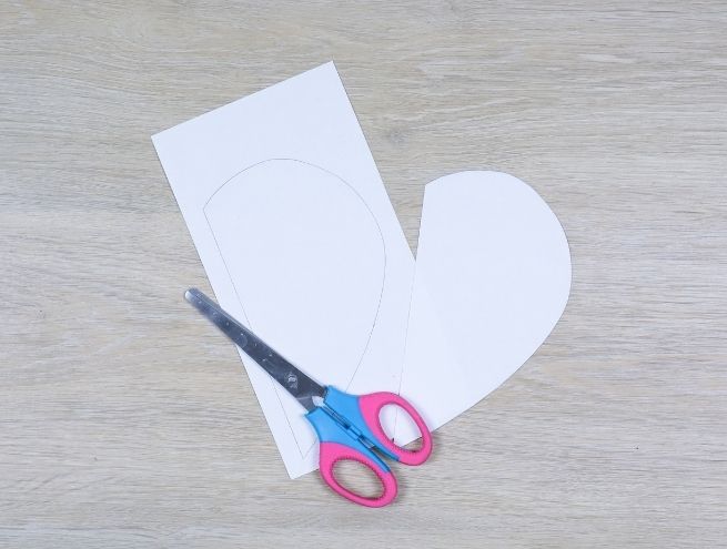 Cut a vase shape out of a cardboard sheet using scissors for a DIY project in recycled cardboard.
