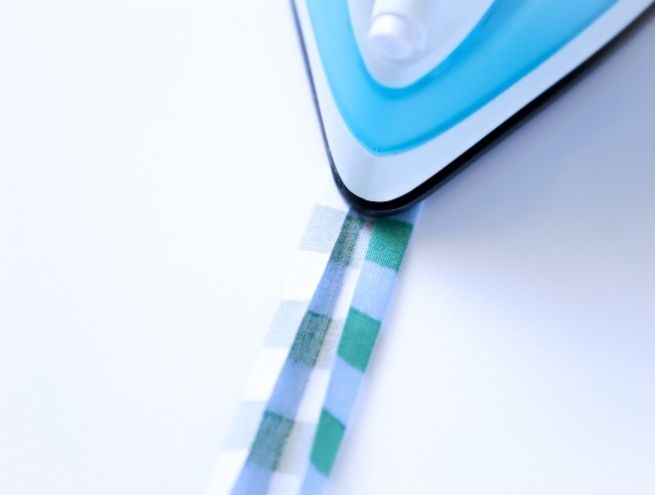 Repassage d'une bande de tissu pour préparer les finitions du calendrier de l'Avent