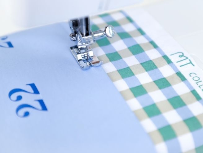 Couture des bandes de tissu vichy sur les poches numérotées du calendrier de l'Avent
